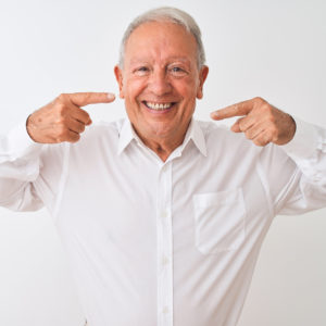 Older Man Smiling Pointing to Teeth with Both Hands