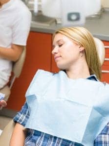 woman in a dental chair with her eyes closed under dental sedation